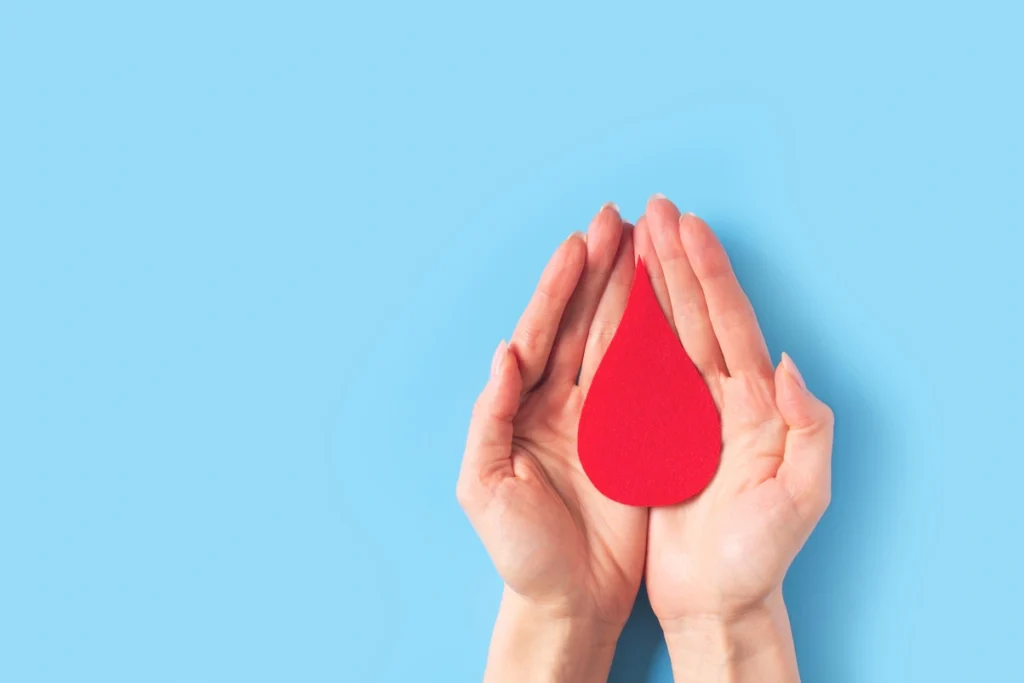 Conmemoración de la hemofilia manos sosteniendo una gota de sangre